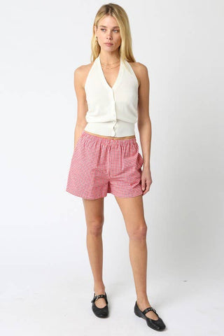 Woman wearing a white sleeveless top and red checkered shorts on a white background