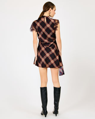 A model from behind wearing a brown and black plaid mini dress with a short puff sleeve, paired with black knee-high boots, against a plain white studio background.