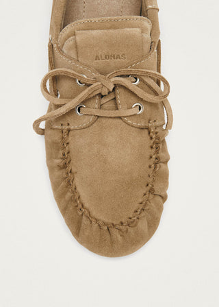 Tan moccasin shoe with laces on a light gray background