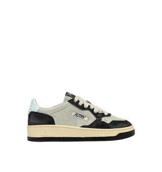 A low-top sneaker by Autry, featuring a light gray glittery upper, black suede overlays, a cream-colored midsole, and a light blue heel tab, shown against a solid off-white background.